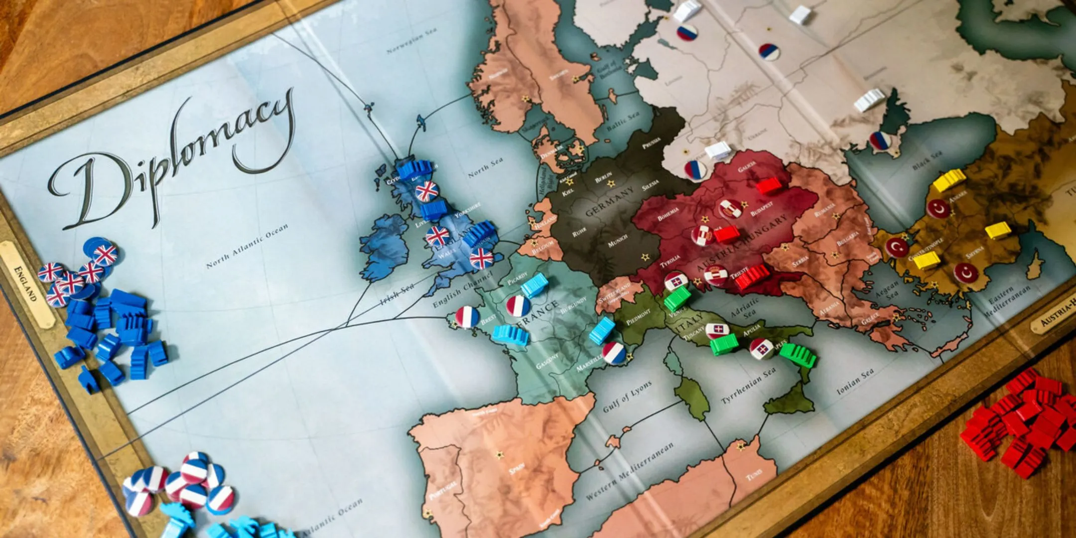 Bàn chơi board game Diplomacy với bản đồ châu Âu, biểu tượng của chiến tranh, liên minh và sự phản bội.