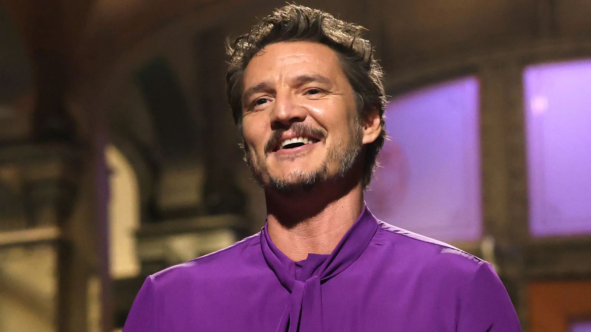 Pedro Pascal với biểu cảm điển hình, có thể đang mỉm cười hoặc suy tư, tượng trưng cho sự nổi tiếng toàn cầu của anh.